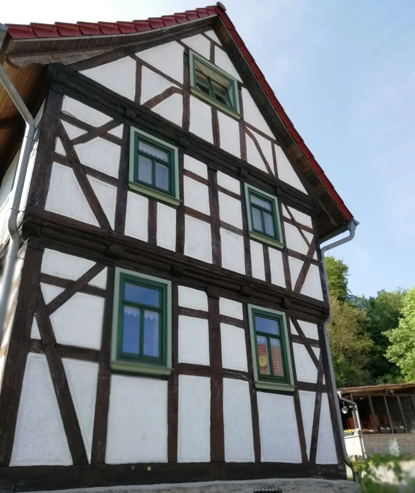 Fachwerkfassade des Forest Guesthouse mit grünen Fenstern und rotem Ziegeldach