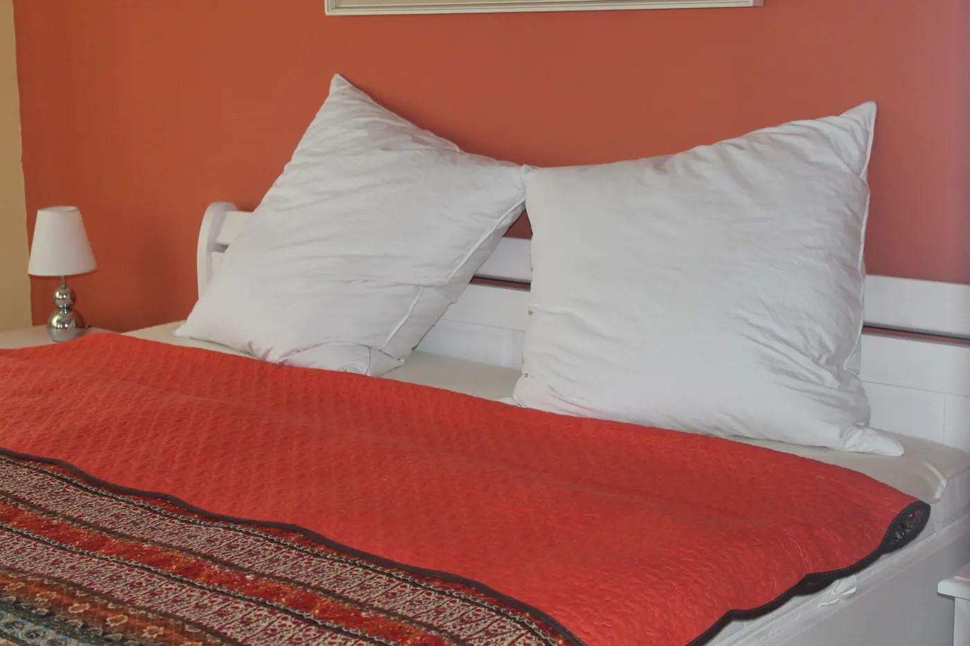 Schlafzimmer mit Doppelbett und roter Tagesdecke