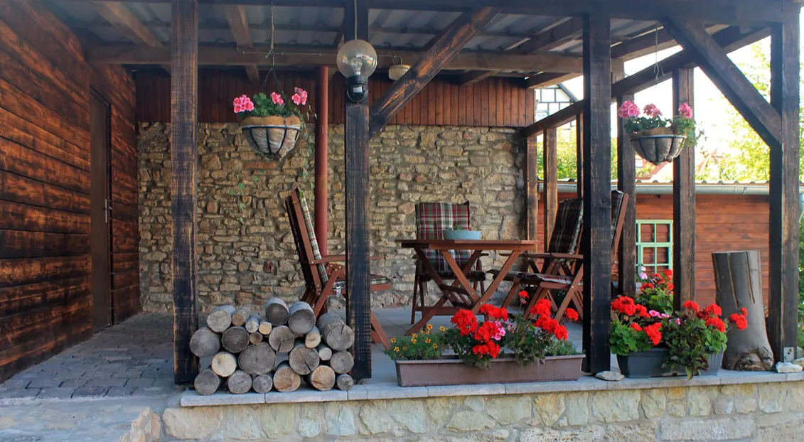 Überdachte Terrasse mit Gartenmöbeln und Blumen